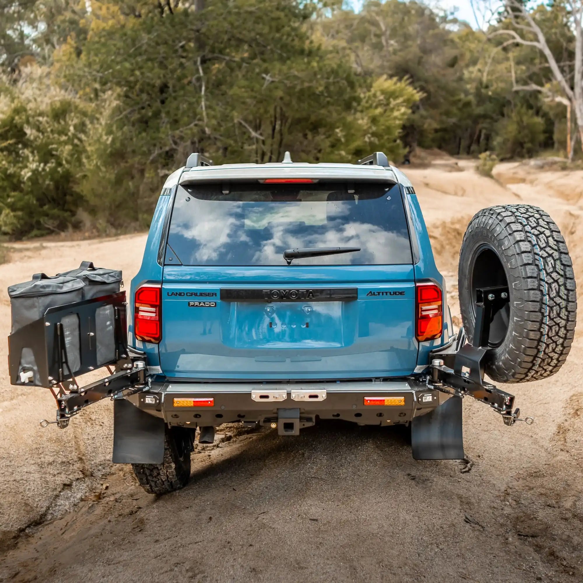 Blue SUV with off-road tire and accessories on a dirt road