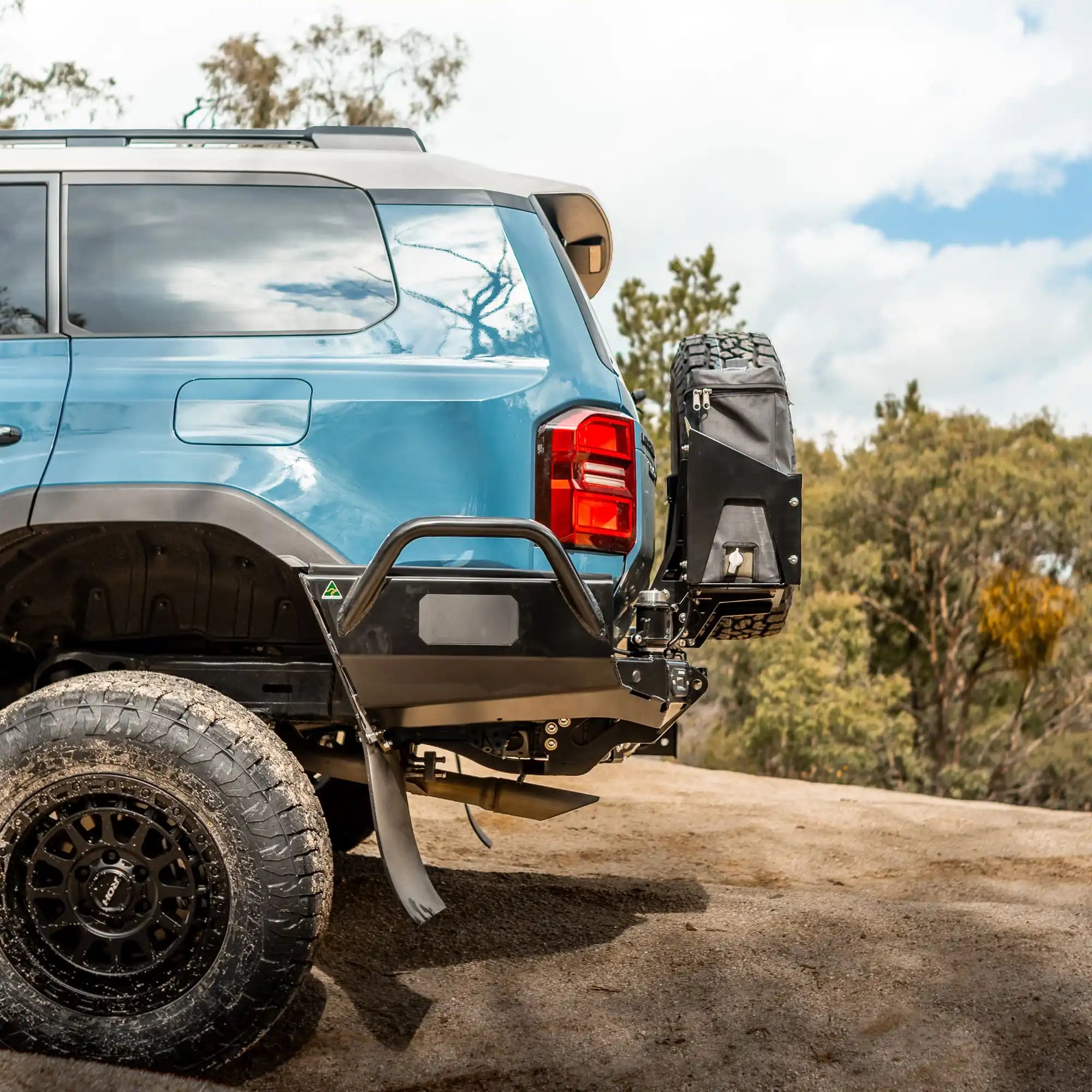 Blue SUV with off-road accessories on a dirt road with trees in the background