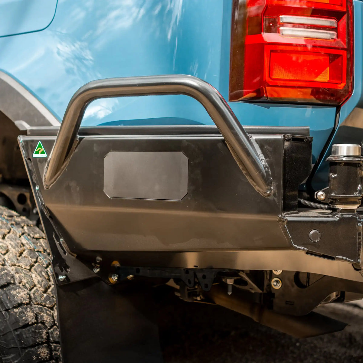 Close-up of a vehicle's rear bumper and tire with a blue background