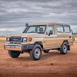 Beige Toyota Land Cruiser in a desert landscape with a cloudy sky.