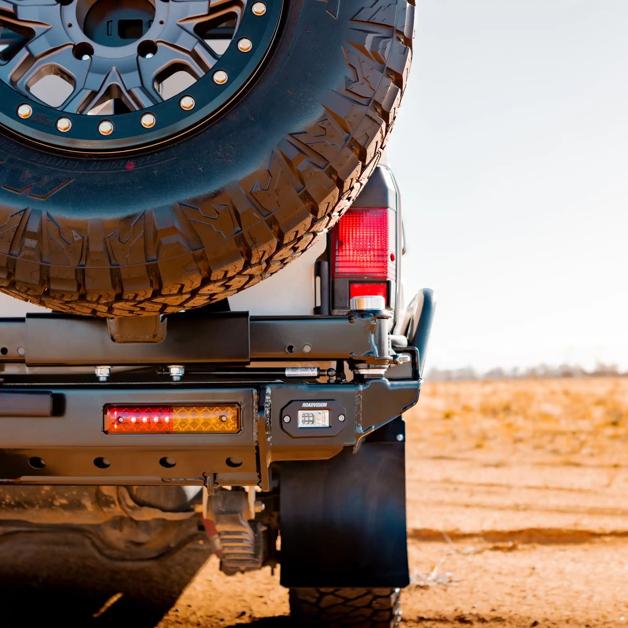 Close-up of a vehicle's rear with a spare tire mounted on a desert landscape