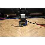 Car interior with wiring and a diesel heater on a wooden floor.