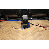 Car interior with wiring and a diesel heater on a wooden floor.