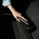 Person using a black vacuum brush on a textured surface