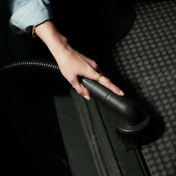 Person using a black vacuum brush on a textured surface