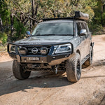 Nissan Patrol SUV on a dirt road with trees in the background