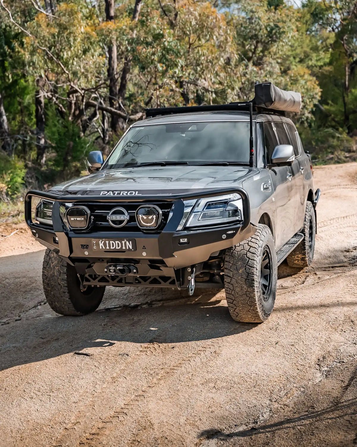 Nissan Patrol SUV on a dirt road with trees in the background