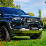 Toyota truck with Lazer branding on a grassy area with trees in the background
