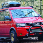 Red Volkswagen van with roof rack in a forest setting with Lazer Lamps Grille Kit for Volkswagen T5.1