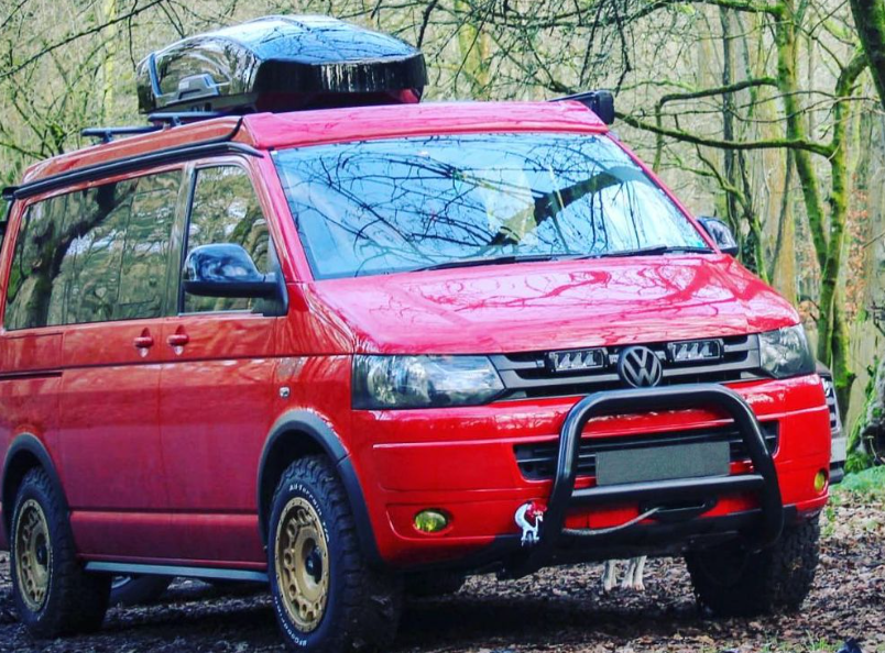 Red Volkswagen van with roof rack in a forest setting with Lazer Lamps Grille Kit for Volkswagen T5.1