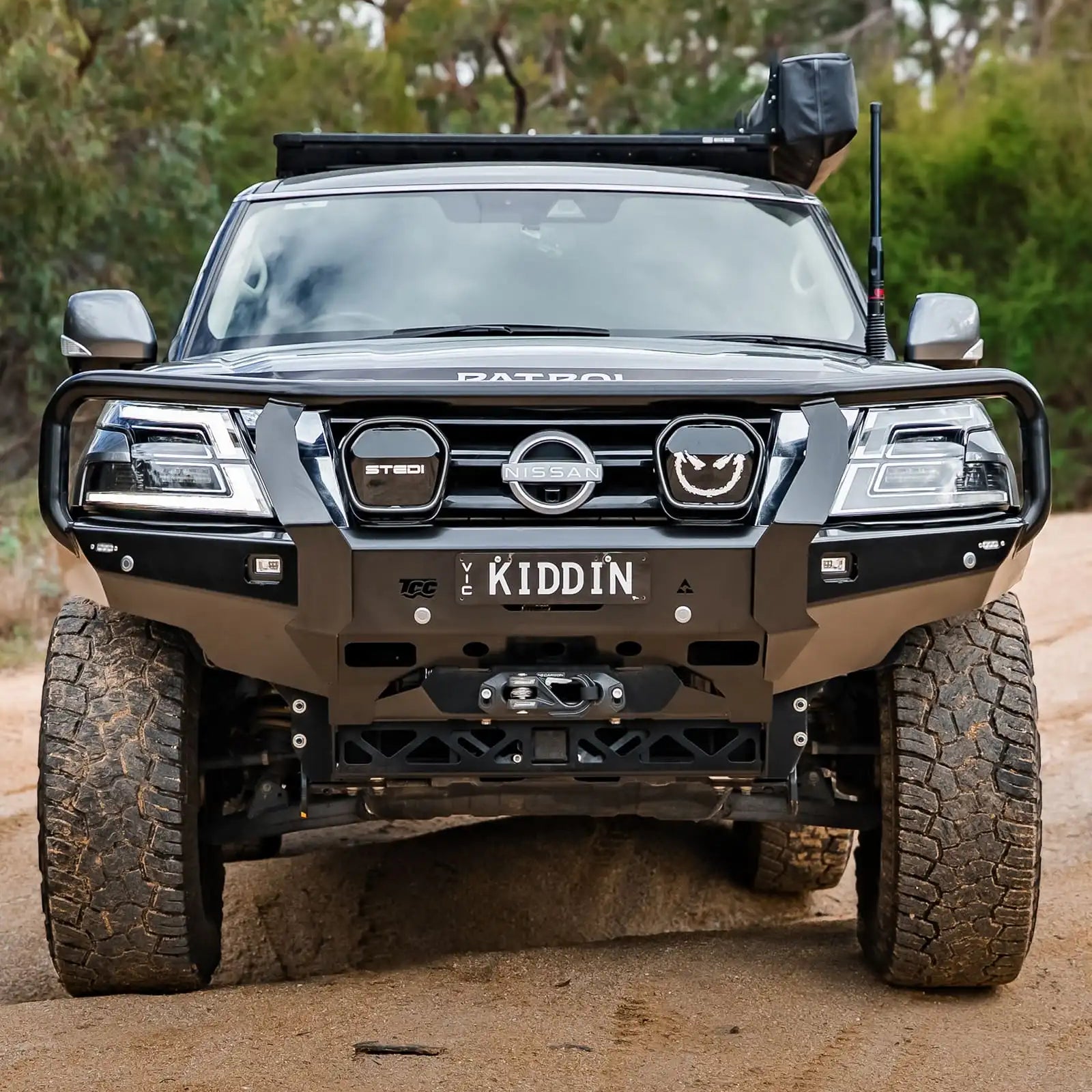 Black Nissan Patrol SUV on a dirt road with 'Kiddin' branding.