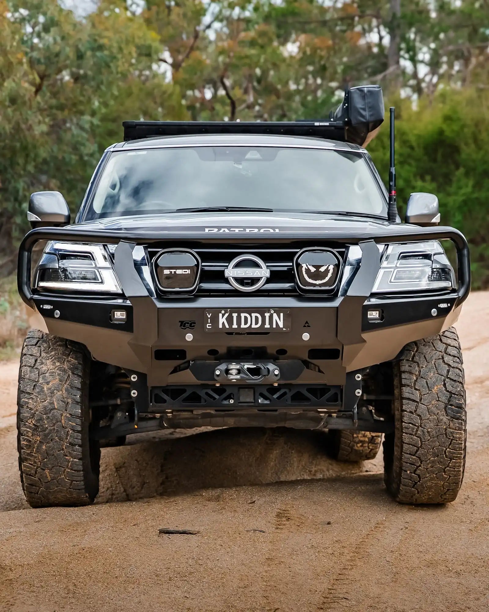 Black Nissan Patrol SUV on a dirt road with 'Kiddin' branding.
