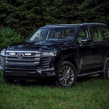 Black Toyota SUV parked on grass with trees in the background