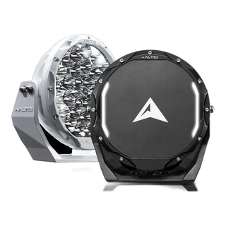 A white and a black ALTIQ Rogue 8.5 driving light photographed against black, the white one showing its reflector face and the black one its arrow-marked cover with the illuminated position-light strip curving across it