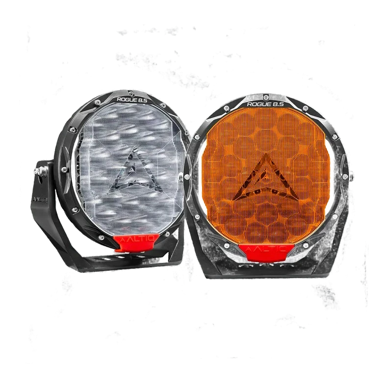 A pair of ALTIQ Rogue 8.5 lights side by side, one fitted with a clear ribbed panoramic cover and the other with an amber cover, both showing the ALTIQ arrow through the lens and the red trim tab at the base