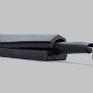 Cut end of the wire concealer, showing the internal round channel that holds the cable and the adhesive strip along the flat base