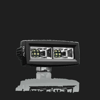 ALTIQ CX4 scene work light at a three-quarter angle, the wide rectangular lens holding two reflector segments each with a cluster of LEDs, the ALTIQ name on the end cheek and the mounting bracket below