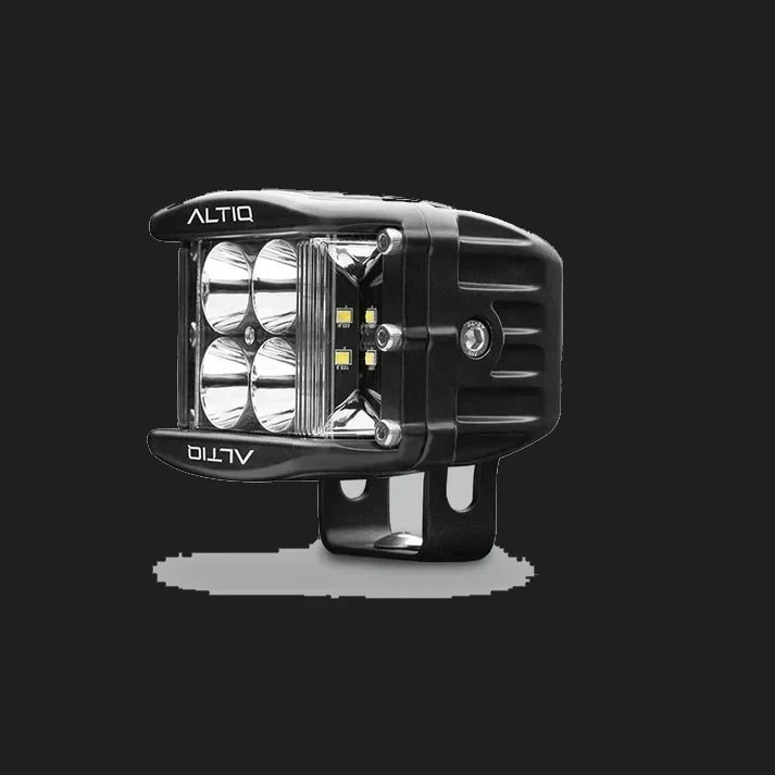 DX4 hybrid work light turned further round, the four spot reflectors and the amber-tinted side flood LEDs both visible with the ALTIQ name on the bezel