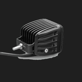 Black DX4 Scene work light from above and to the side, showing the deeply finned cast heatsink, the stainless bracket and threaded stud, and the lead leaving the rear