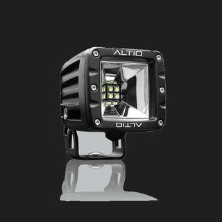 Black DX4 Scene work light at a three-quarter angle, the ALTIQ name on the bezel above a square reflector with nine LEDs, mounted on its black bracket
