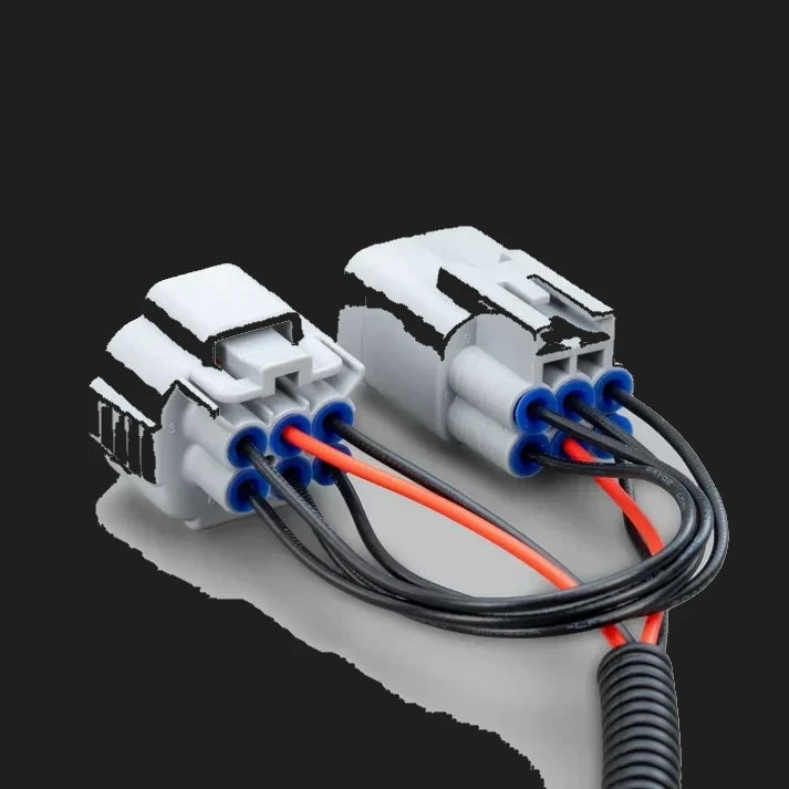 The two grey headlight connectors on the adaptor, one male and one female, with blue seals around the terminals and red and black wires looping between them into a corrugated sleeve