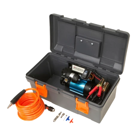 ARB single piston compressor in its grey plastic travel case with the lid open, the compressor mounted inside with its battery clamps, and the orange coiled air hose, tyre chuck and inflation adaptors laid out in front