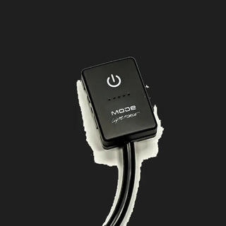 Lightforce MODE touch switch seen at an angle, a black rectangular button with a power symbol, a row of five indicator dots and the MODE by Lightforce name, on a moulded body with a lead leaving the back