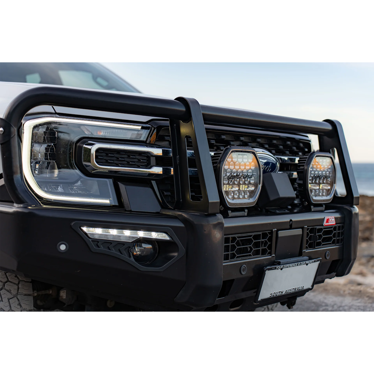 Pair of Lightforce BEAST driving lights fitted to the bullbar of a white Ford Ranger, photographed in daylight