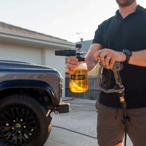 Person holding a pressure washer with a Blahst foam bottle in front of a truck – Blahst Foam Cannon