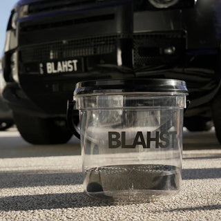 Clear wash bucket with 'Blahst' branding in front of a black vehicle.