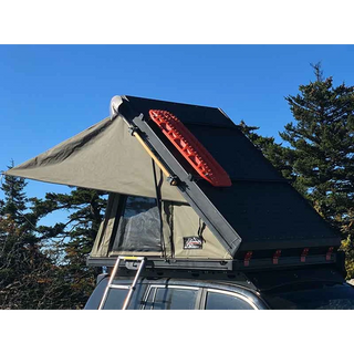 Bush Company AX27 Clamshell Rooftop Tent attached to a vehicle with trees in the background