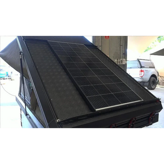 Solar panel on the roof of a vehicle with a building and car in the background