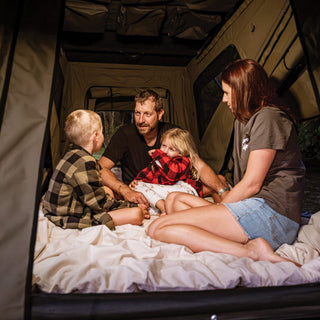Family of four sitting on the mattress inside the Bush Company TX27