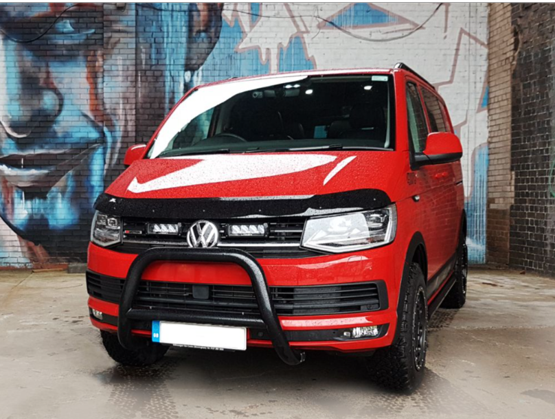 Red Volkswagen van in front of a graffiti-covered wall