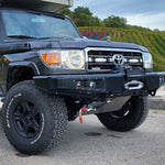 Black Toyota Land Cruiser off-road vehicle with large tires and Lazer Lamps Grille Mount Kit for Toyota LandCruiser 70 Series ST4 Evo on a paved surface.