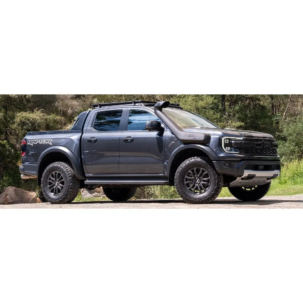 Gray Ford Raptor truck on a road with trees in the background