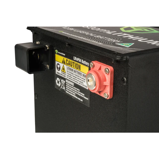 Close-up of a battery with warning labels and a red terminal on a black background