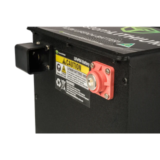 Close-up of a battery with warning labels and a red terminal on a black background