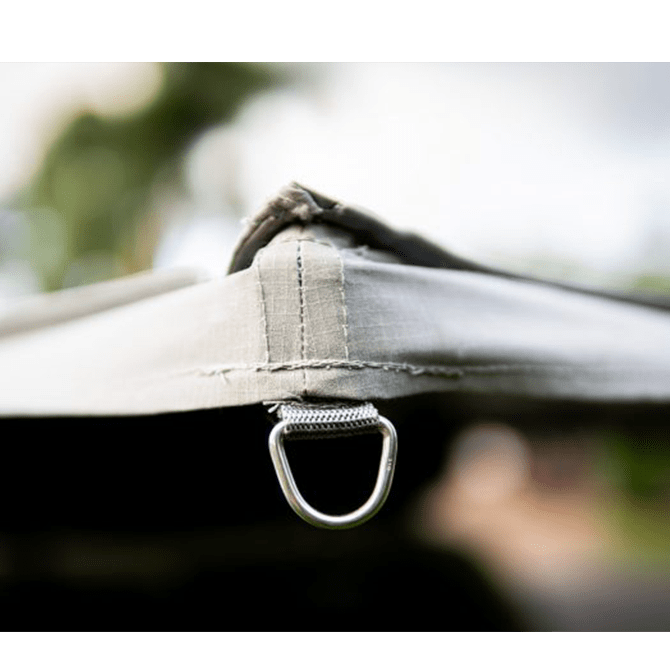 Close-up of a tent strap with a metal ring against a blurred natural background