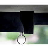 Close-up of a black strap with a metal ring attachment against a blurred green background