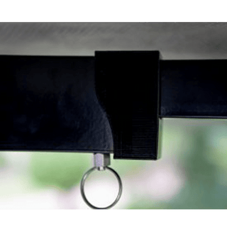 Close-up of a black strap with a metal ring attachment against a blurred green background