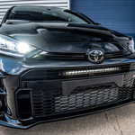 Black Toyota car with a prominent grille and headlights in front of a garage door.