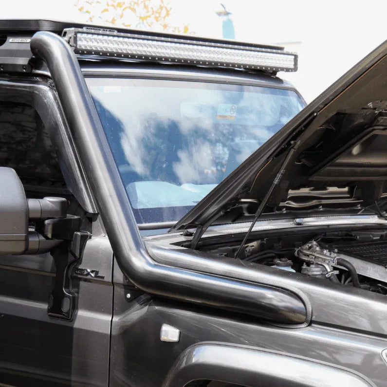 Close-up of a vehicle with a roof rack and LED light bar, outdoors.