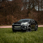Black Toyota truck parked on a grassy area with trees in the background with Lazer Lamps Bumper Beam Mount Kit – Toyota Hilux (2017–2020)