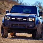 Blue Toyota Prado 250 on a dirt road with a clear sky and Lazer Lamps ST4 Evolution Grille Kit – Land Cruiser 250 (2024+)