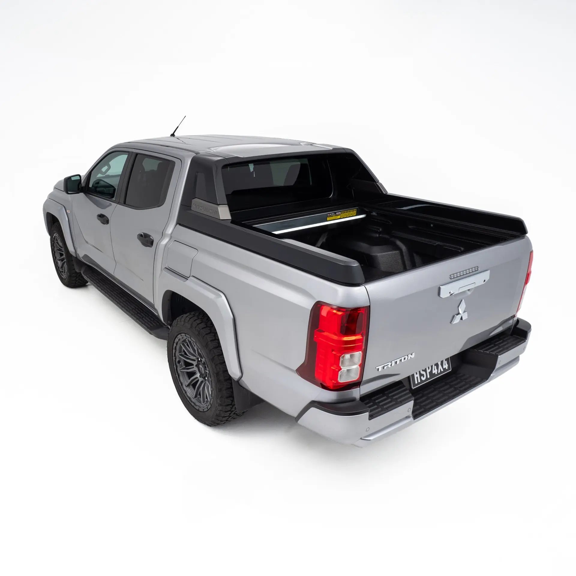 Silver Mitsubishi Triton pickup truck with a black tonneau cover on a white background