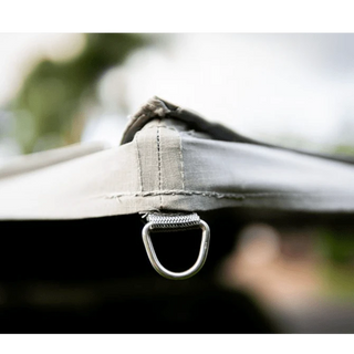 Close-up of a tent strap with a metal ring against a blurred natural background