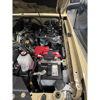 Open car hood revealing engine and battery components.