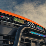 Close-up of a vehicle's front grille with 'R-Motion' branding against a cloudy sky.