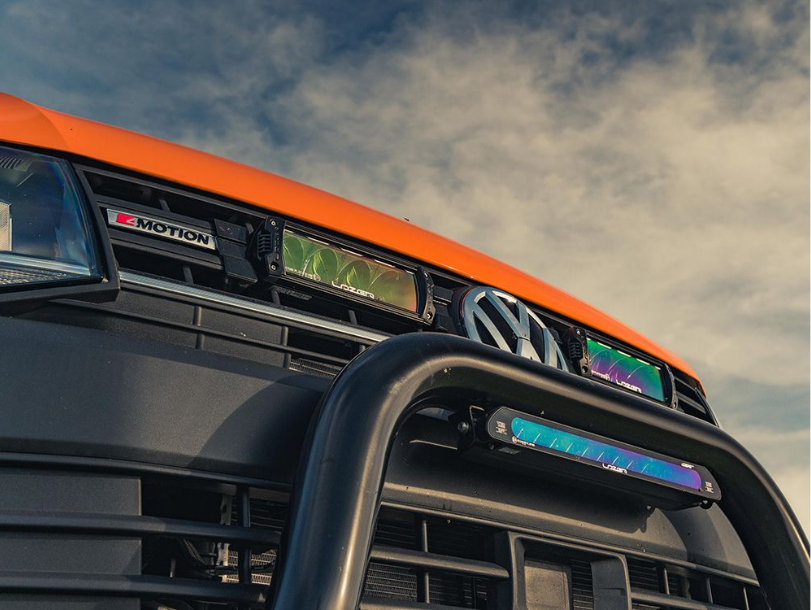 Close-up of a vehicle's front grille with 'R-Motion' branding against a cloudy sky.